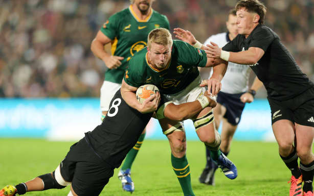 Pieter-Steph du Toit of South Africa tackled by All Blacks players Ardie Savea and Cam Roigard.