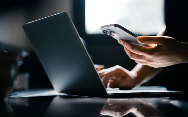 Close-up shot of a woman using mobile device with Two-Factor Authentication (2FA) security while logging in securely to her laptop. Privacy protection, internet and mobile security