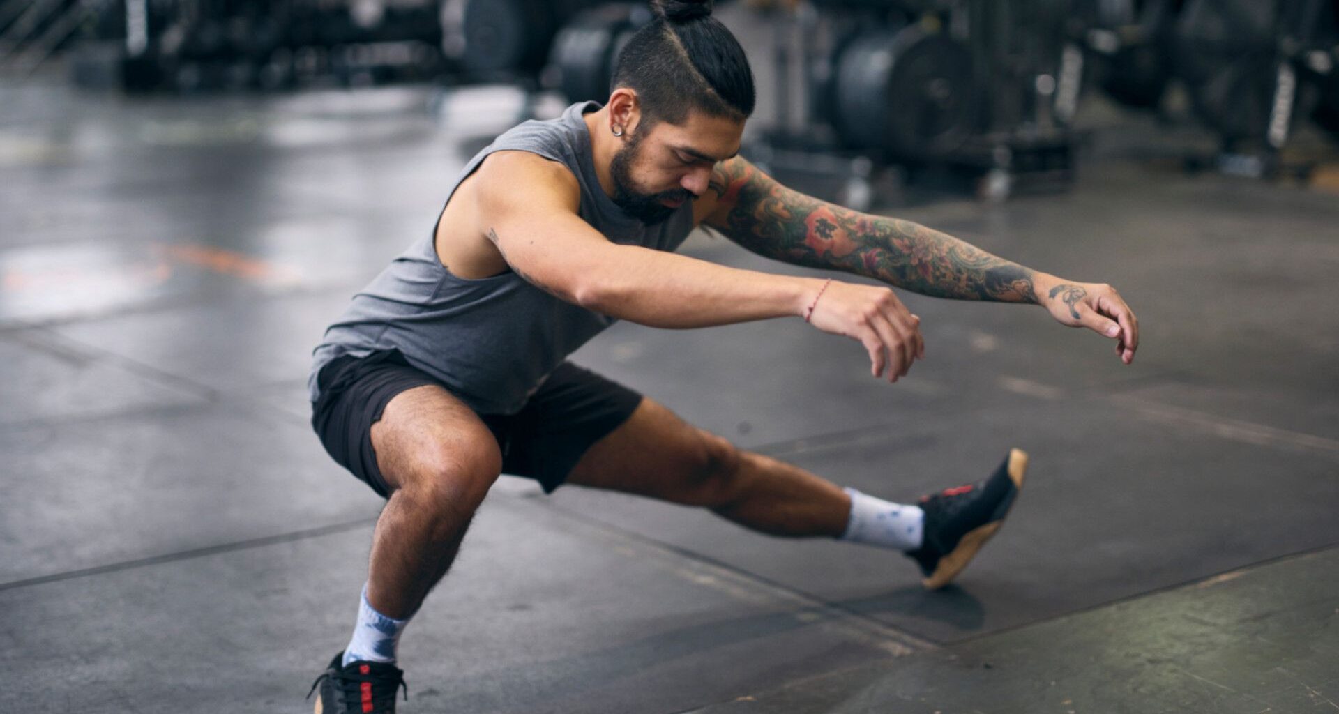 A man performing a bodyweight lower body exercise: cossack squat