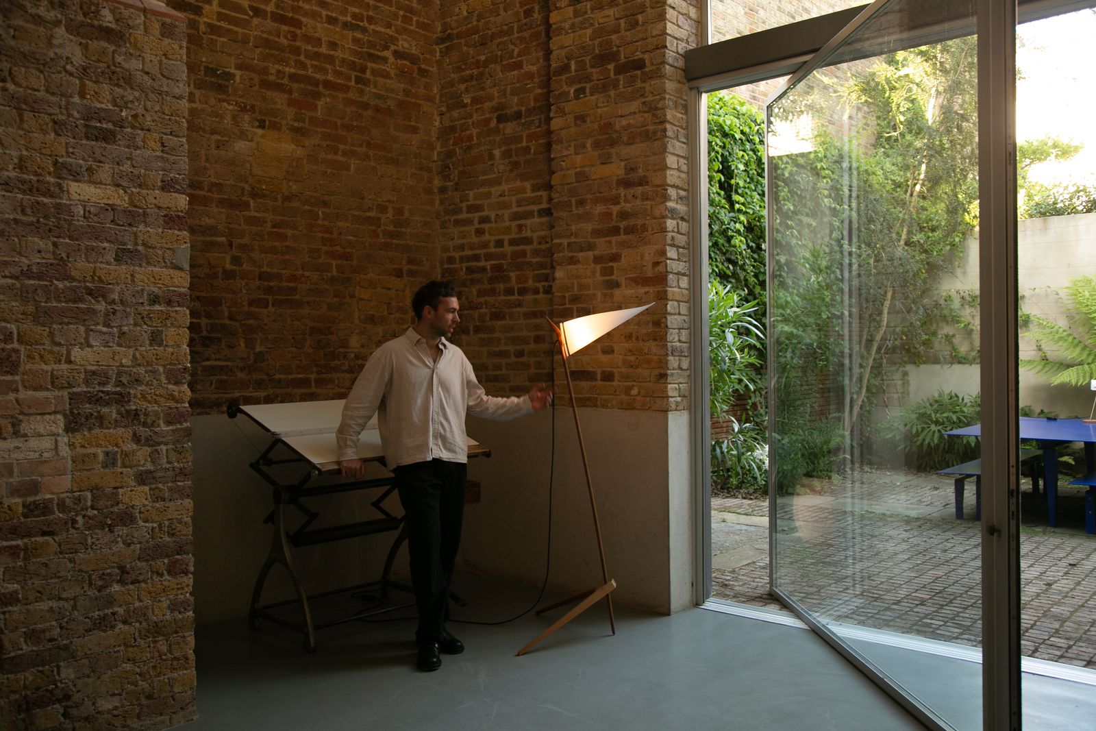 Image may contain Tom Brake Lamp Adult Person Furniture Table Clothing Footwear Shoe Desk Floor Lamp and Plant
