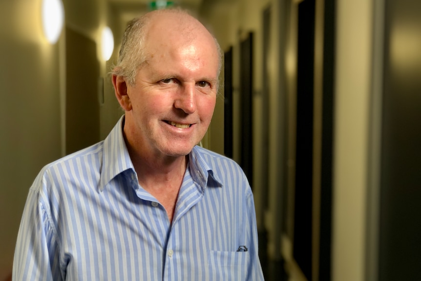 A man in a blue collared shirt smiles at camera.