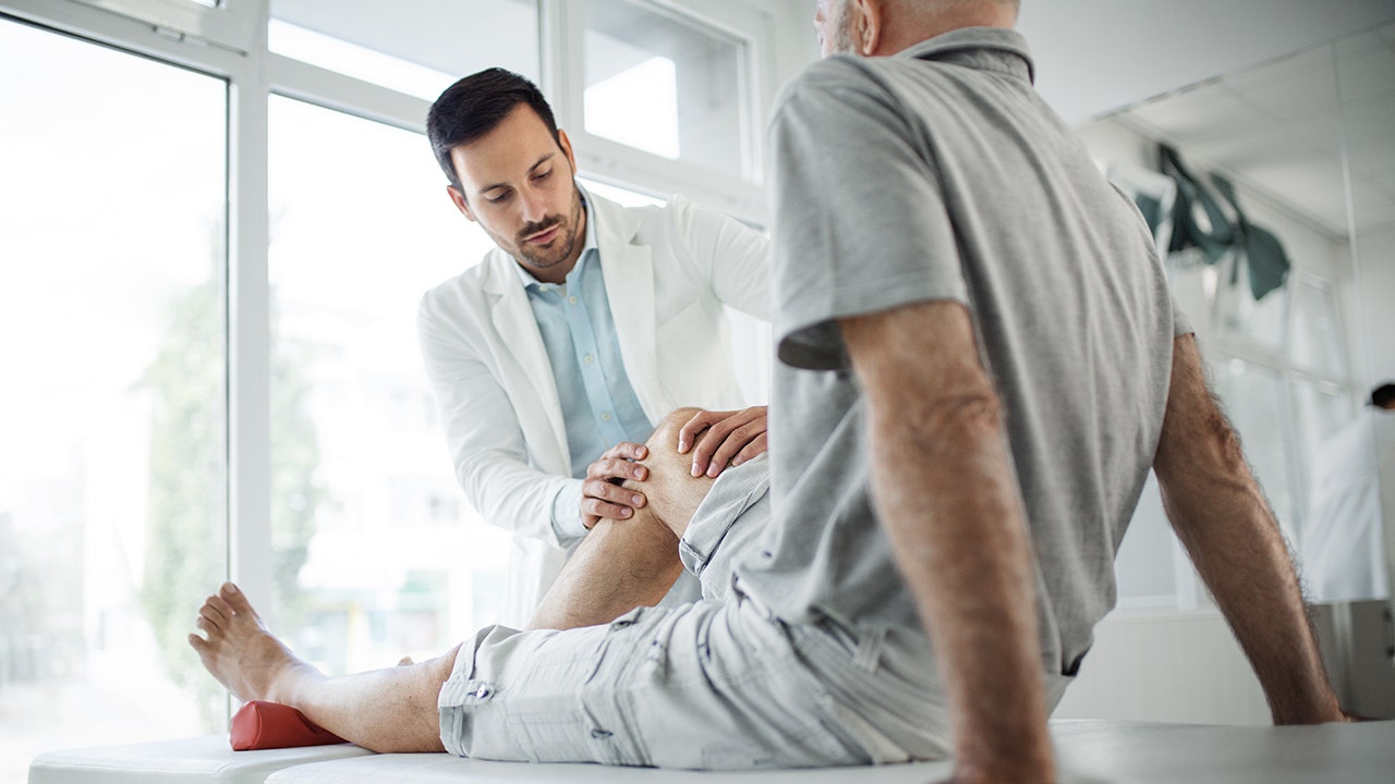 doctor examines a male patient's knee