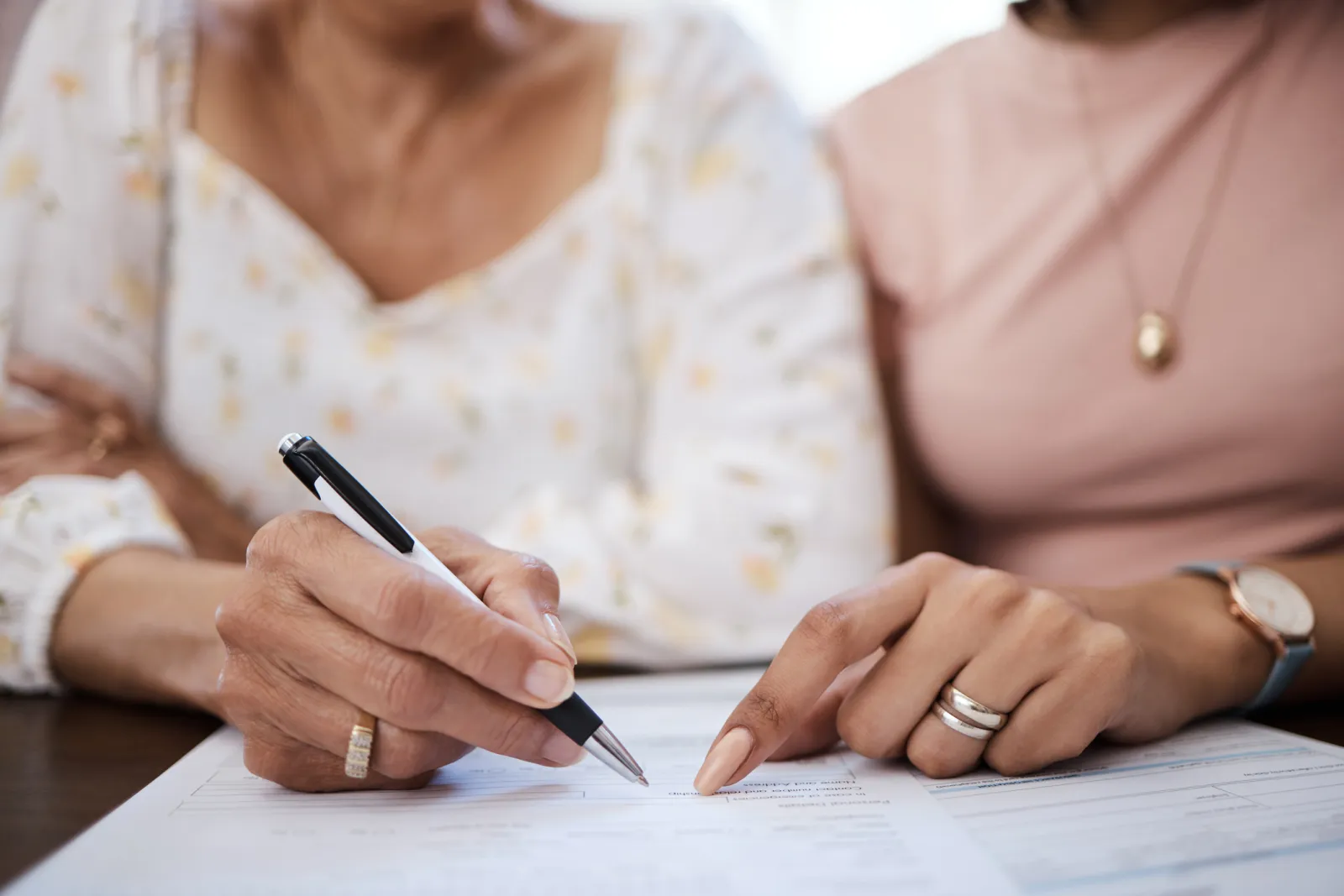 Stock image/file photo: An older woman and younger woman signing documents.