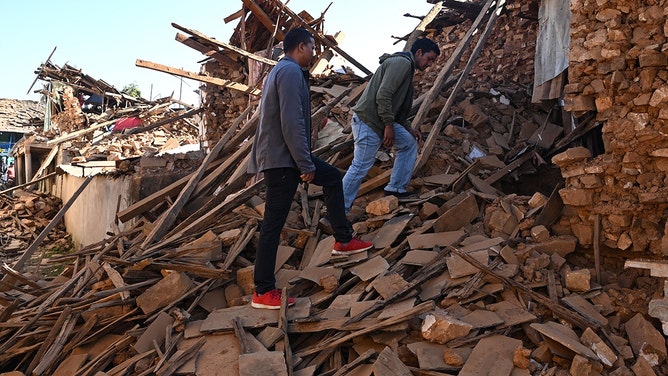 People walk over the ruins of houses in the aftermath of an earthquake at Jajarkot district on November 4, 2023.