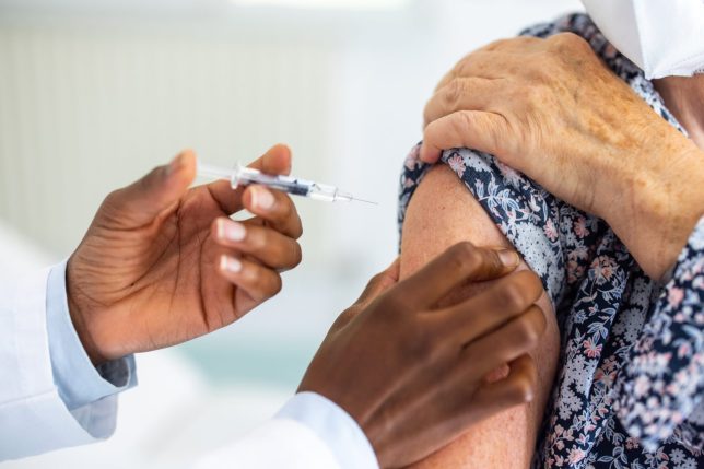 Close-up of a healthcare worker hands giving injection on the arm of female in the clinic. Doctor giving flu shot to a woman in the medical clinic.