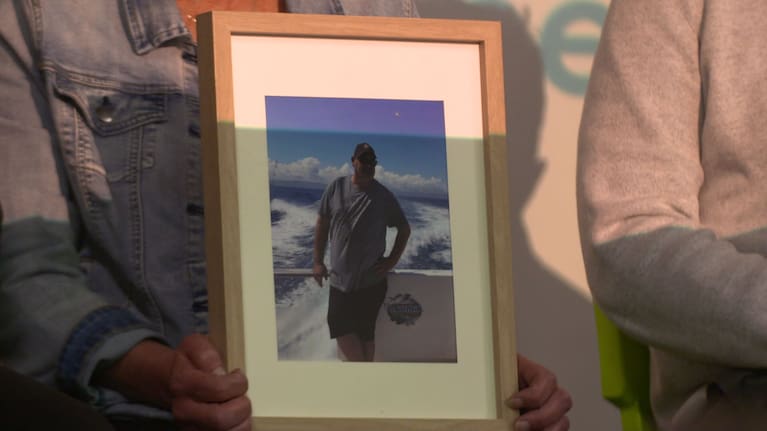 A photo of Brent is held by members of his family.