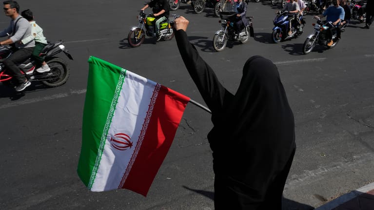 A woman chants slogan as she holds an Iranian flag while motorcyclists ride during a state-organized motorcycle parade called "Janfada," meaning "Sacrifice for Iran,", in Tehran, Iran, Friday, Sept. 25, 2026.