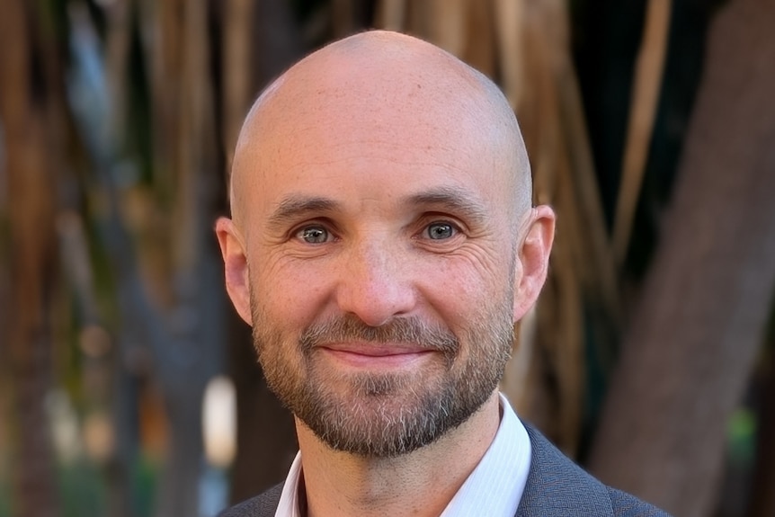 Milo Barham wears a grey suit.