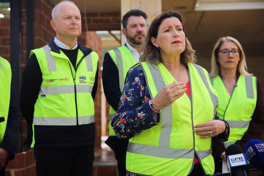 WA Fisheries Minister Jackie Jarvis at a media conference wearing a hi-vis vest, in front of others also in hi-vis.