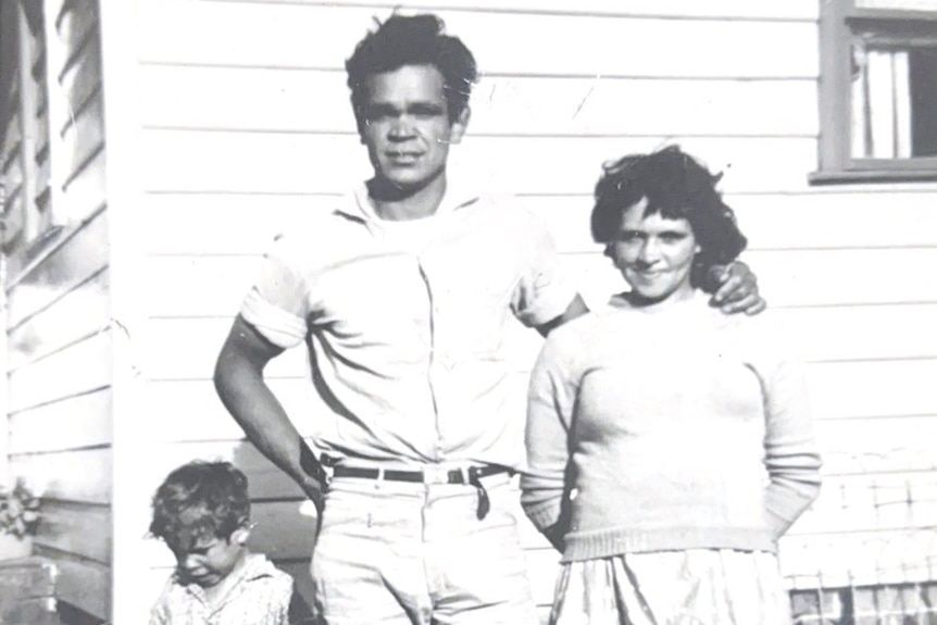 A black and white photo of Mr Cruse as a small child standing next to his dad who has his arm around Mr Cruse's mum.