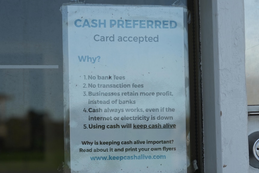 A laminated signs stuck to a shop window, it reads: cash preferred, card accepted.