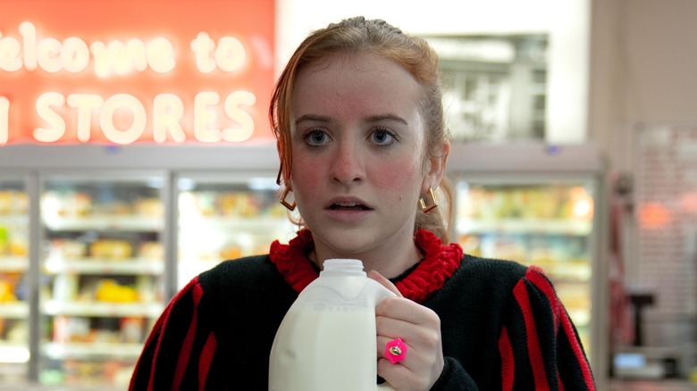 A red-in-the-face Jane holding a carton of milk in a supermarket in 
