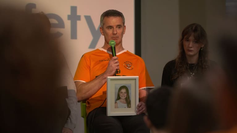 Gareth Hall speaks, holding a picture of his daughter.