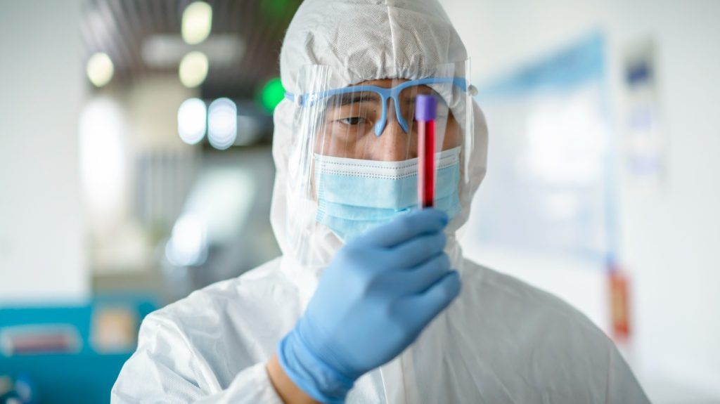 A scientist looking at a blood vial.