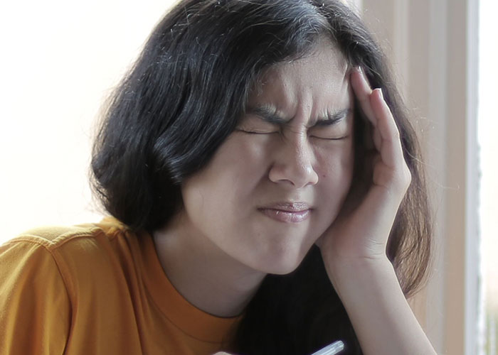 Woman with a severe headache, showing symptoms of pain, as doctors stop and stare.