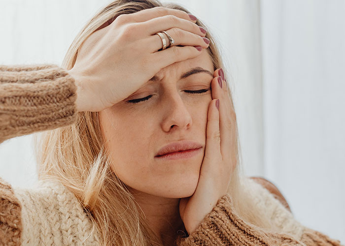 A woman holding her head and jaw, indicating symptoms of pain. These symptoms can make doctors stop and stare.