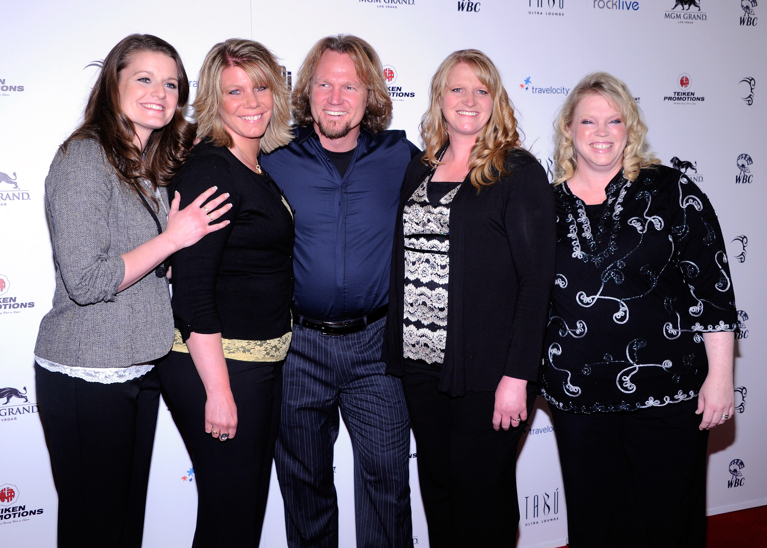 Five people smiling on a red carpet in front of MGM Grand and sponsor banners.