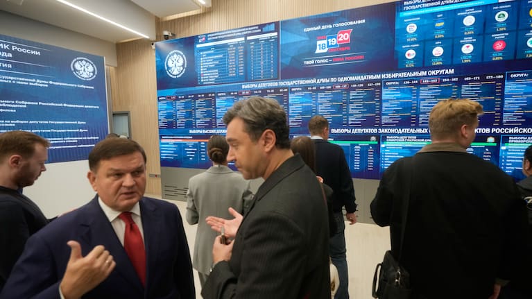 People stand next to video screens sowing preliminary voting results for Russian parliamentary elections at Russia's Central Election Committee headquarters, in Moscow, Russia, Monday, Sept. 21, 2026.