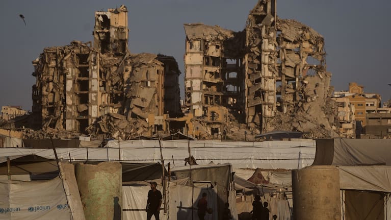 People walk past tents sheltering displaced Palestinians amid the ruins of buildings destroyed by Israeli airstrikes during the war with Hamas, in Gaza City, Monday, August 17, 2026.