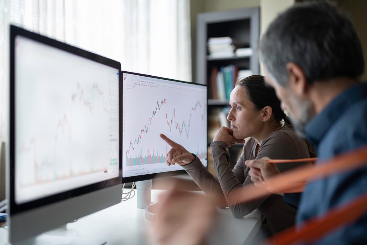 Analysts studying stock charts on desktop monitors.