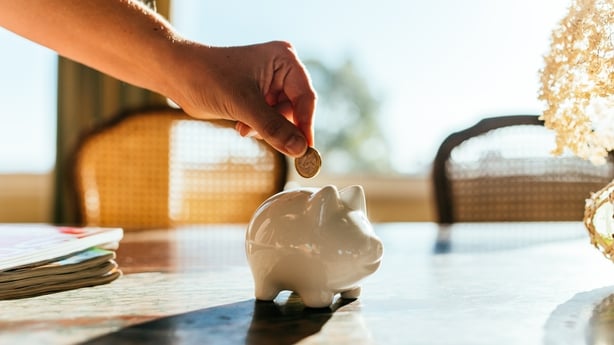 Woman putting savings in a white piggy bank.