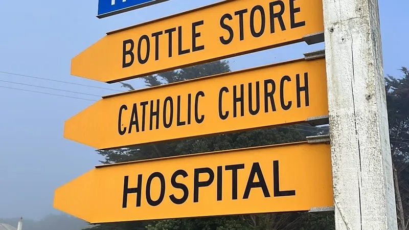 a street sign with yellow tabs signalling hospital road, bottle store, catholic church and hospital