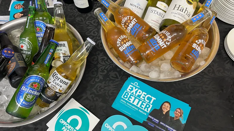 two ice buckets filled with Speights and Heiken beer bottles next to supporter merch for the Opportunity Party