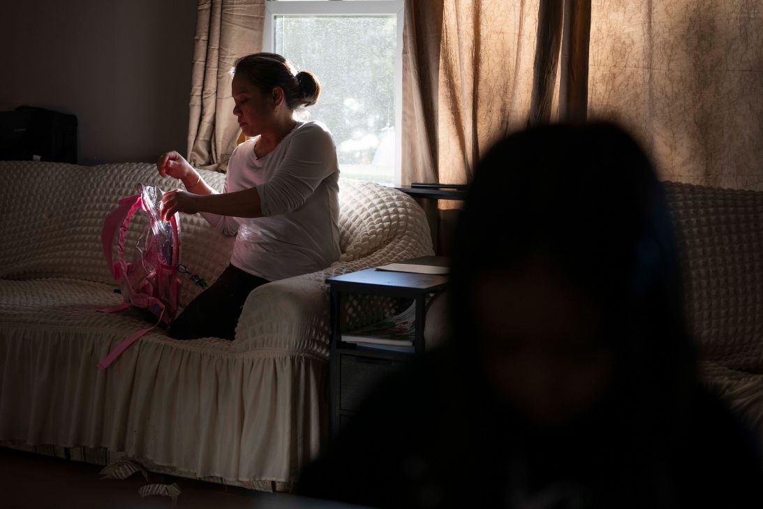 Marichu puts her daughter’s school work away after coming home from work. All three of her daughters are now in school locally.