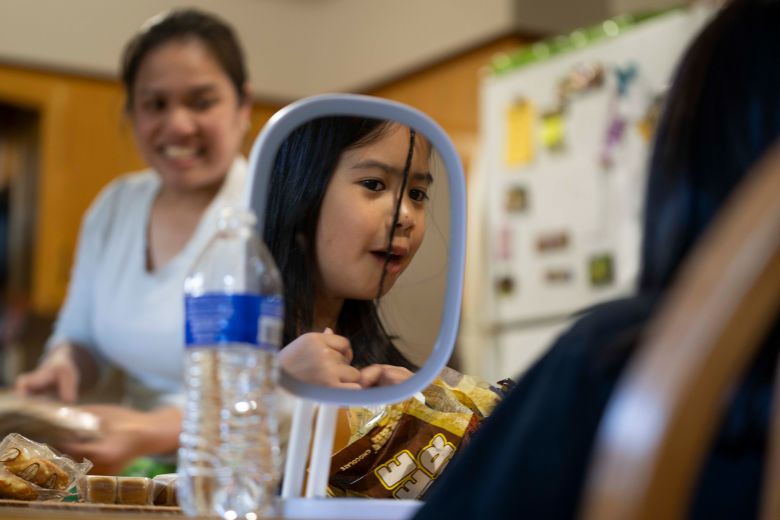 Marichu's daughter Kate works on her hair while her mom cleans up dinner,. Marichu got settled in North Dakota before her daughters arrived from the Philippines.