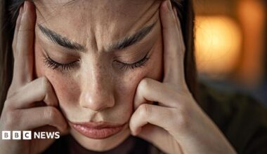 A woman looking stressed out wit her fingers pressed against her temples