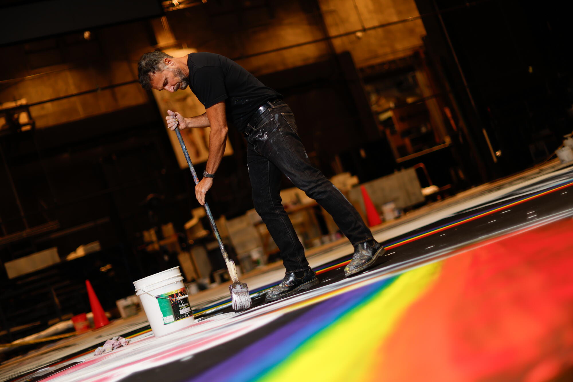 An artist paints a rainbow on a large canvas.