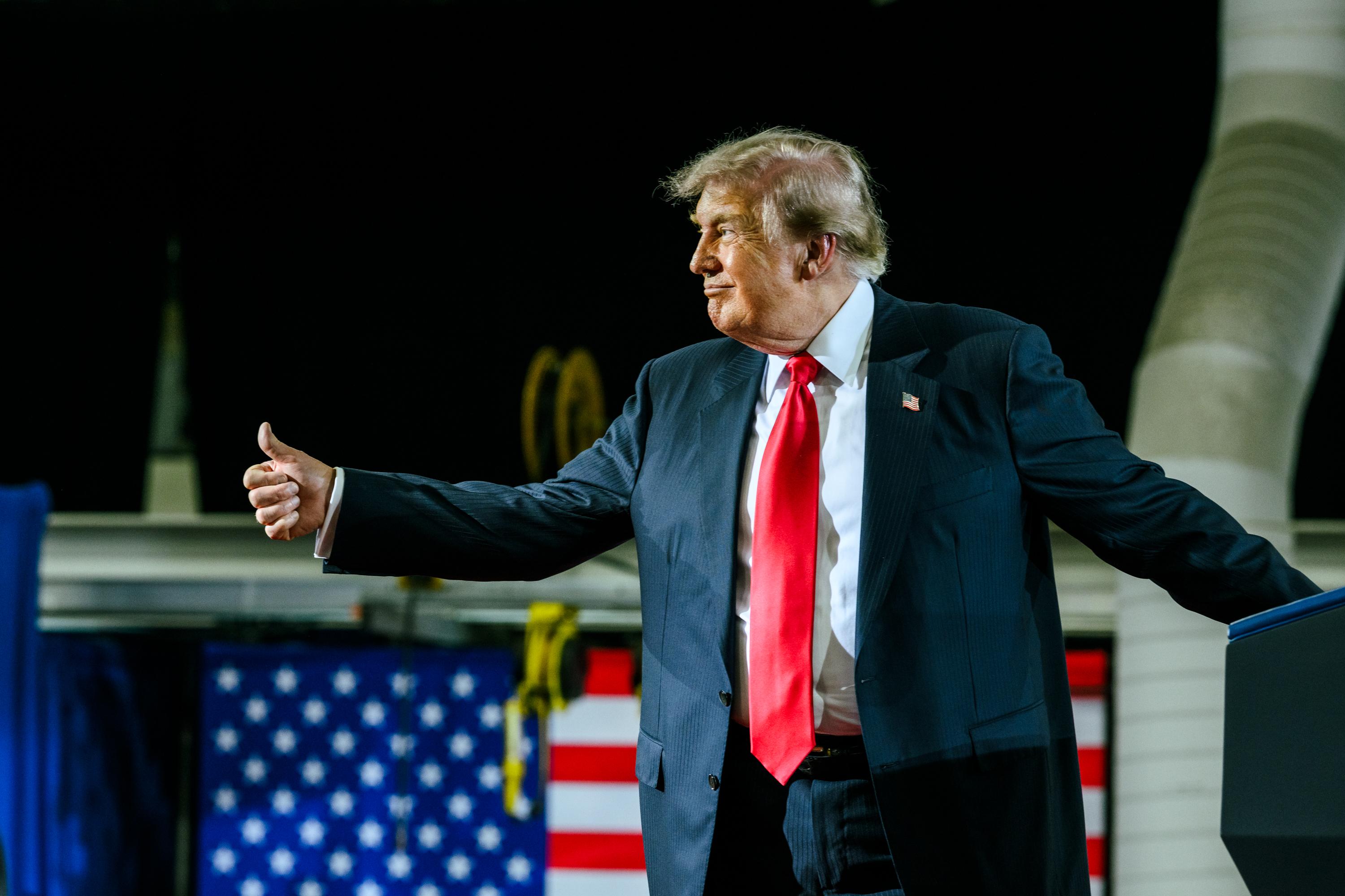 Donald Trump is giving a thumbs-up to the crowd while on stage.