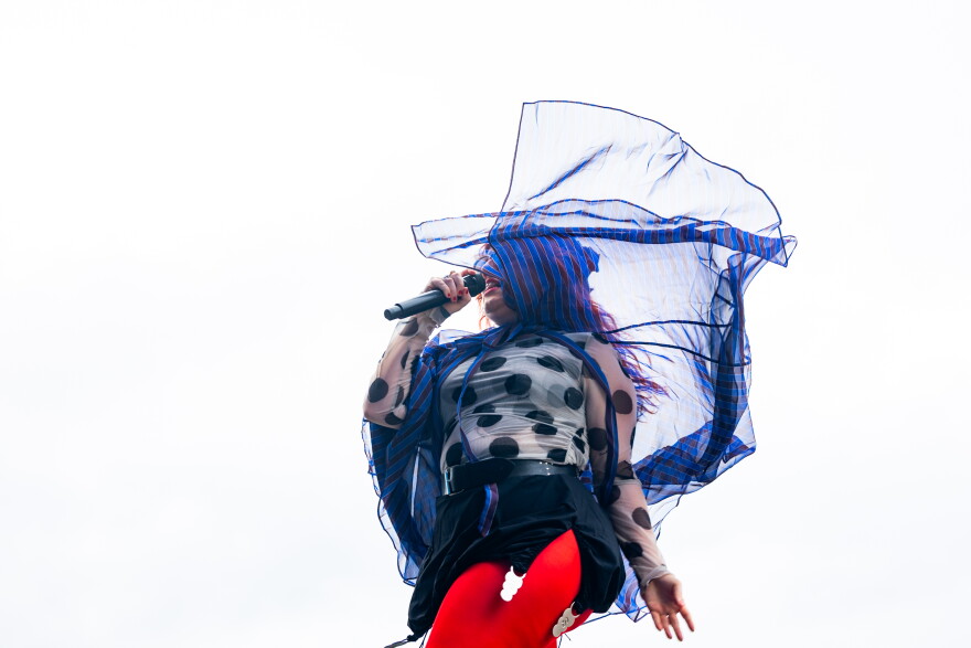 A woman performs on stage with her face obscured by a scarf.