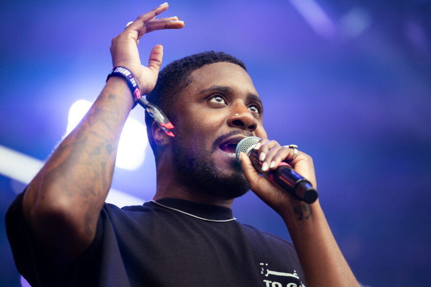 A man raises his arm in the air as he sings into a microphone.