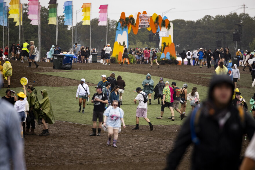 People walk past an area with astroturf while mud is shown surrounding it.