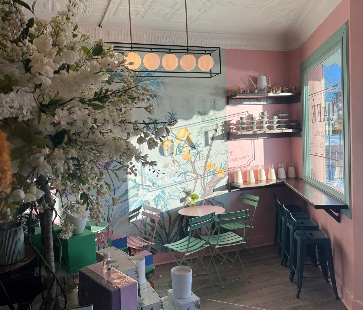 Inside a BloomBar Café et Fleurs shop with pink walls, a floral mural and mint green bistro chairs