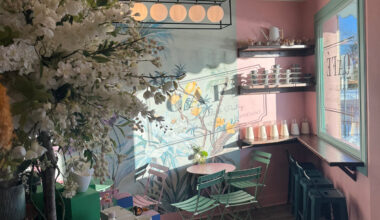 Inside a BloomBar Café et Fleurs shop with pink walls, a floral mural and mint green bistro chairs