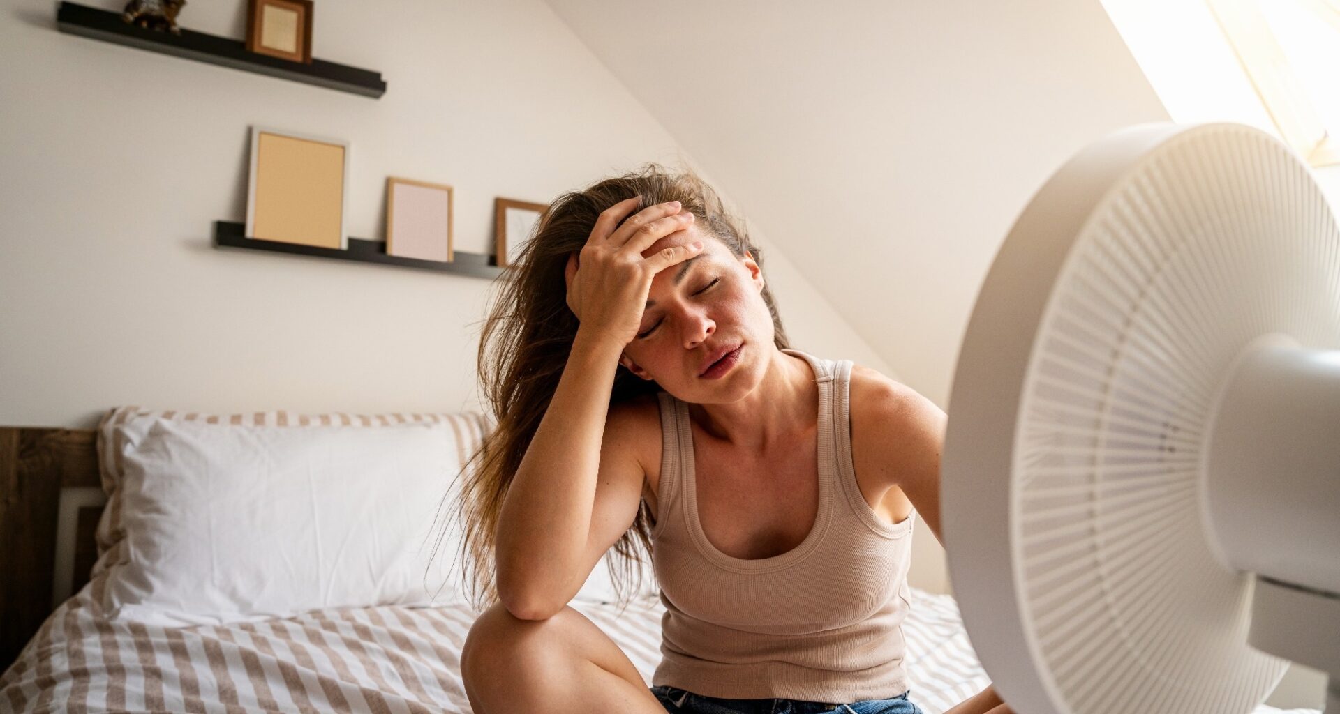 Overheated woman trying to cool down with fan at home