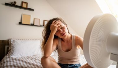 Overheated woman trying to cool down with fan at home
