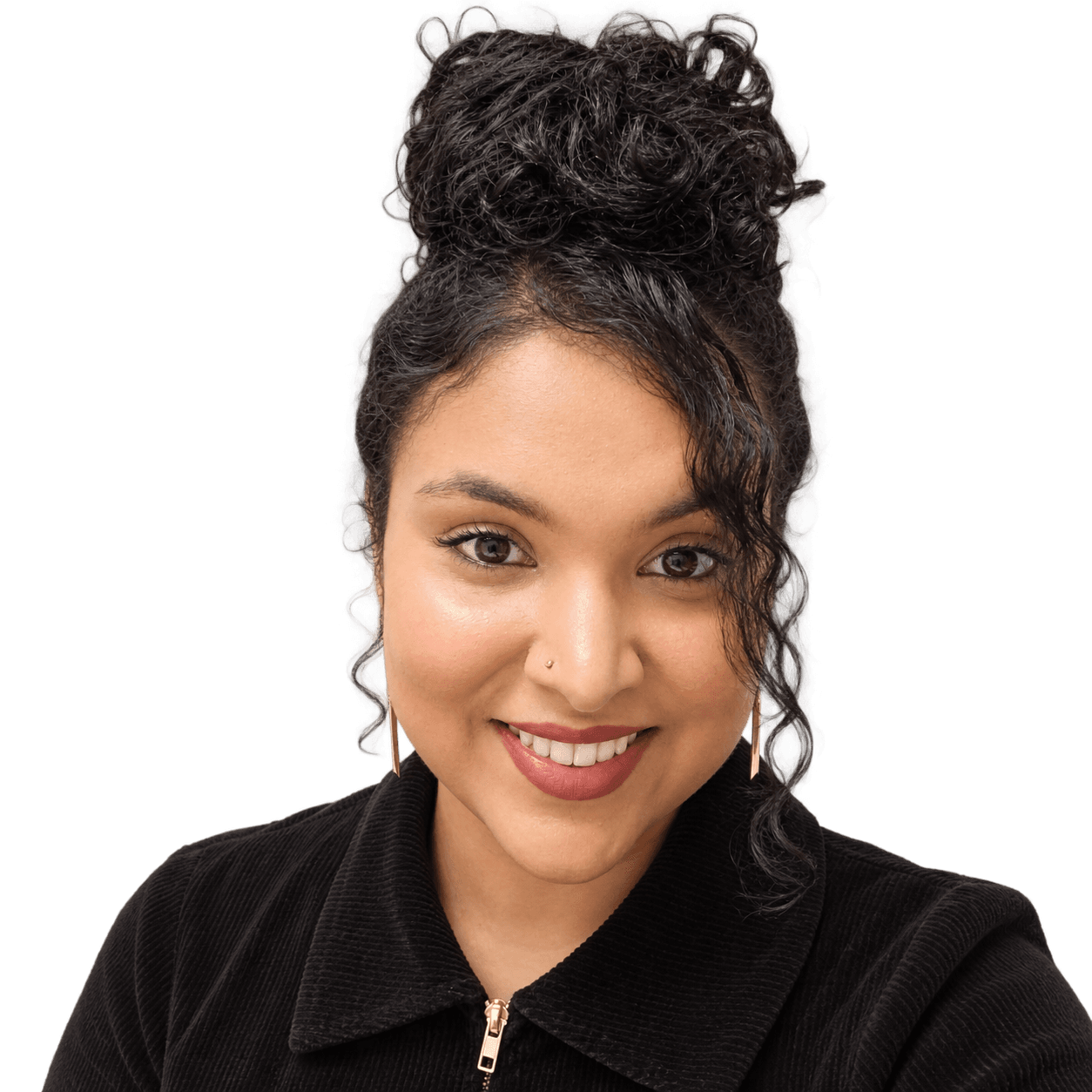 Smiling woman with dark curly hair in a top bun, wearing a black corduroy jacket and gold earrings
