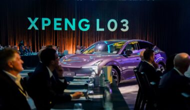A purple Xpeng L03 SUV displayed among seated guests beneath illuminated XPENG L03 lettering.
