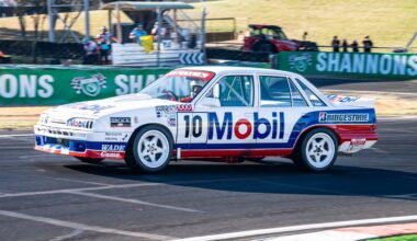 White, red and blue number 10 Mobil-liveried Holden Commodore touring car cornering on a race track.