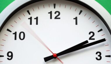 Closeup on top half of clock with a moving red second hand.