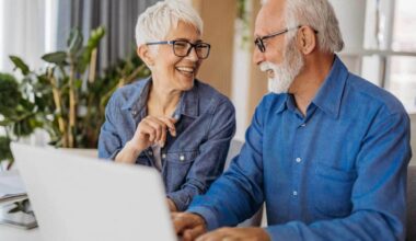 A couple working on a laptop laugh as they discuss their ASX share portfolio.