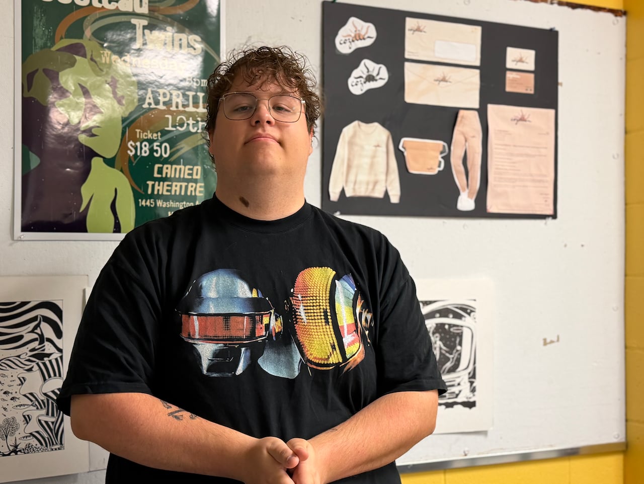 A student stands in a classroom with posters on the wall