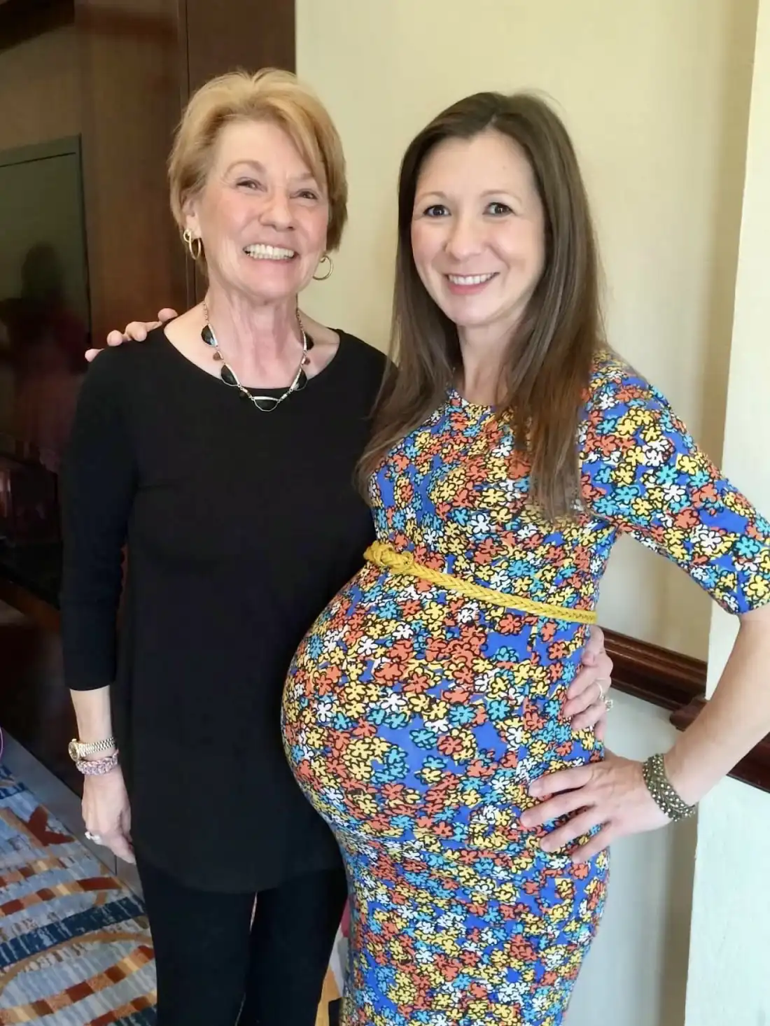 Meghan Maher, who is pregnant, stands with her mom Connie Cadwell. Both women are smiling broadly. 