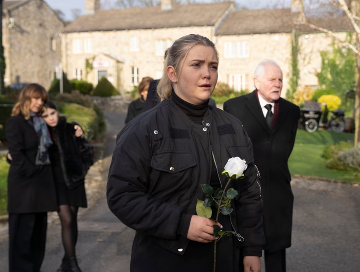 18_01_emm_heath_funeral_02 Cathy carries a white rose in Heath's funeral procession in a scene from Emmerdale