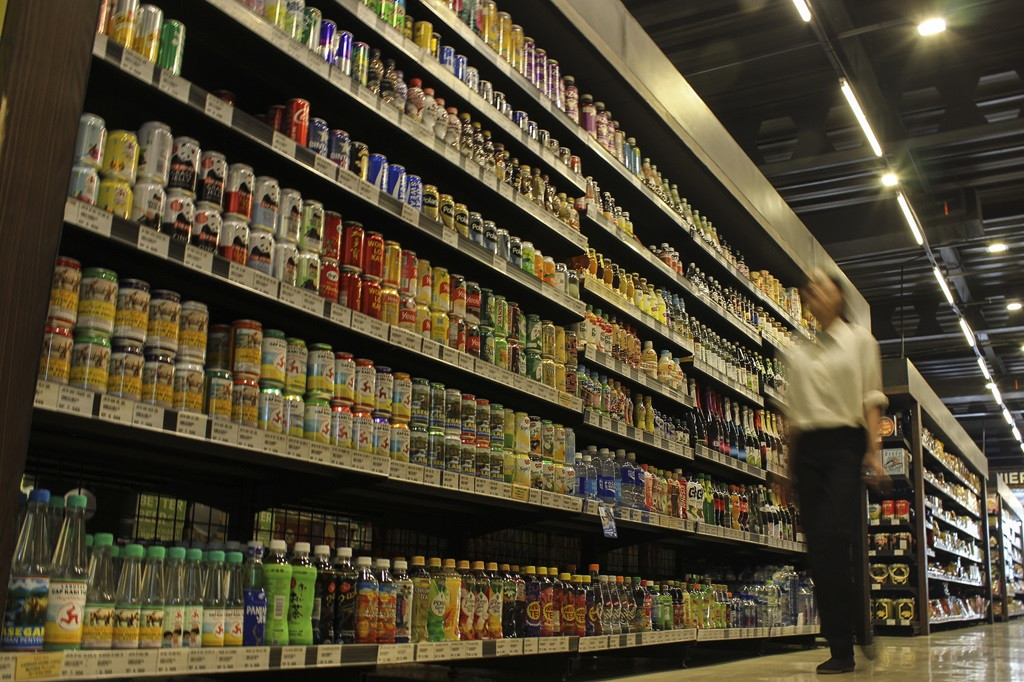 A woman walks down an aisle of sugar-sweetened beverages at a supermarket in Jakarta on Dec. 14, 2023.