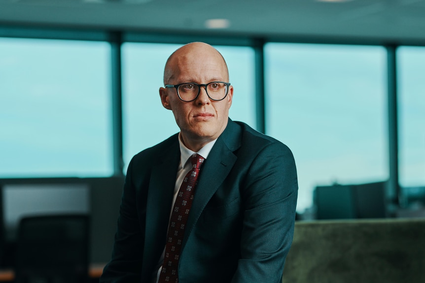A man in a suit sits on a chair.