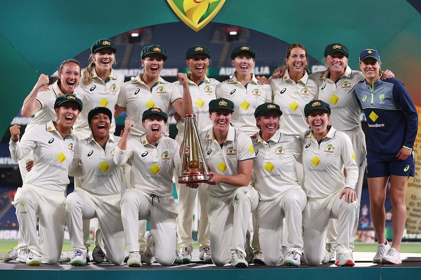 The Australian team huddle together with the Ashes trophy to celebrate their victory